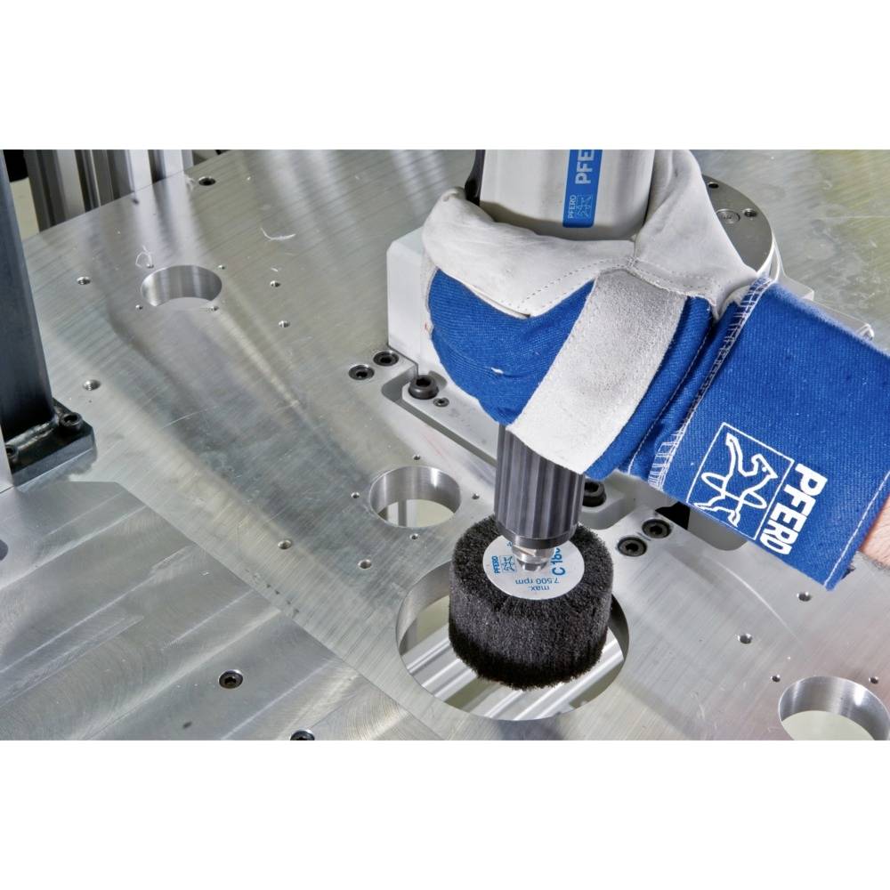 Ein Arbeiter poliert eine Metalloberfläche mit einem elektrischen Polierwerkzeug. Das Werkzeug hat eine runde Bürste.