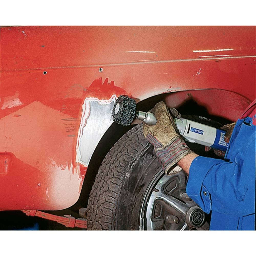 Eine Person schleift mit einem Werkzeug ein rotes Autoblechteil ab, um es für die Lackierung vorzubereiten.