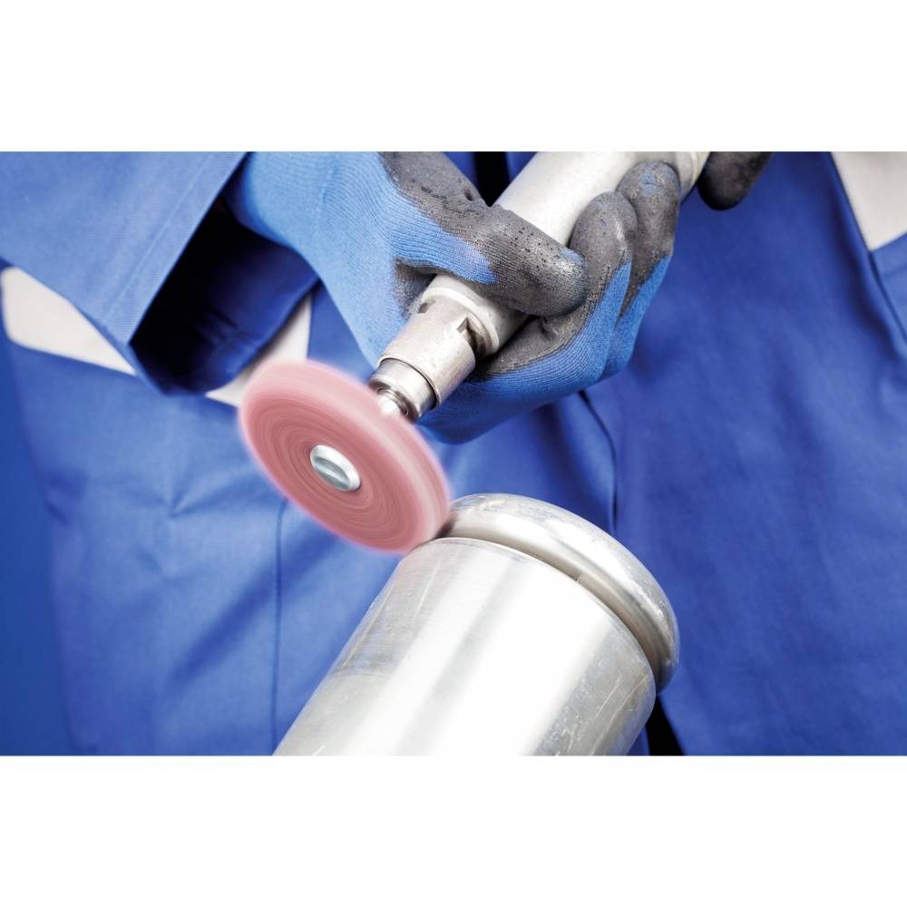 Eine Person in blauer Arbeitskleidung und mit Handschuhen poliert eine Metalloberfläche mit einer elektrischen Poliermaschine.