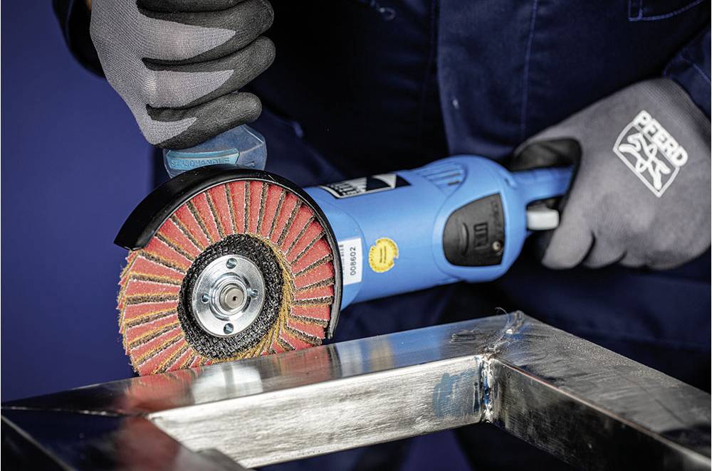 Eine Person schleift mit einem elektrischen Winkelschleifer Metall. Sie trägt Sicherheitshandschuhe. Der Schleifteller ist rot.