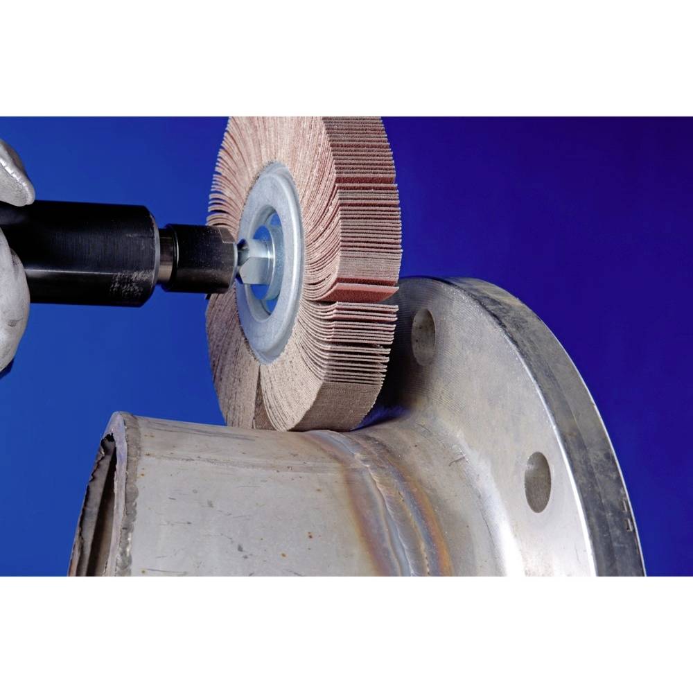 Eine Maschine schleift die Oberfläche eines Metallflansches mit einer rotierenden Schleifscheibe, um eine glatte Oberfläche zu erzeugen.