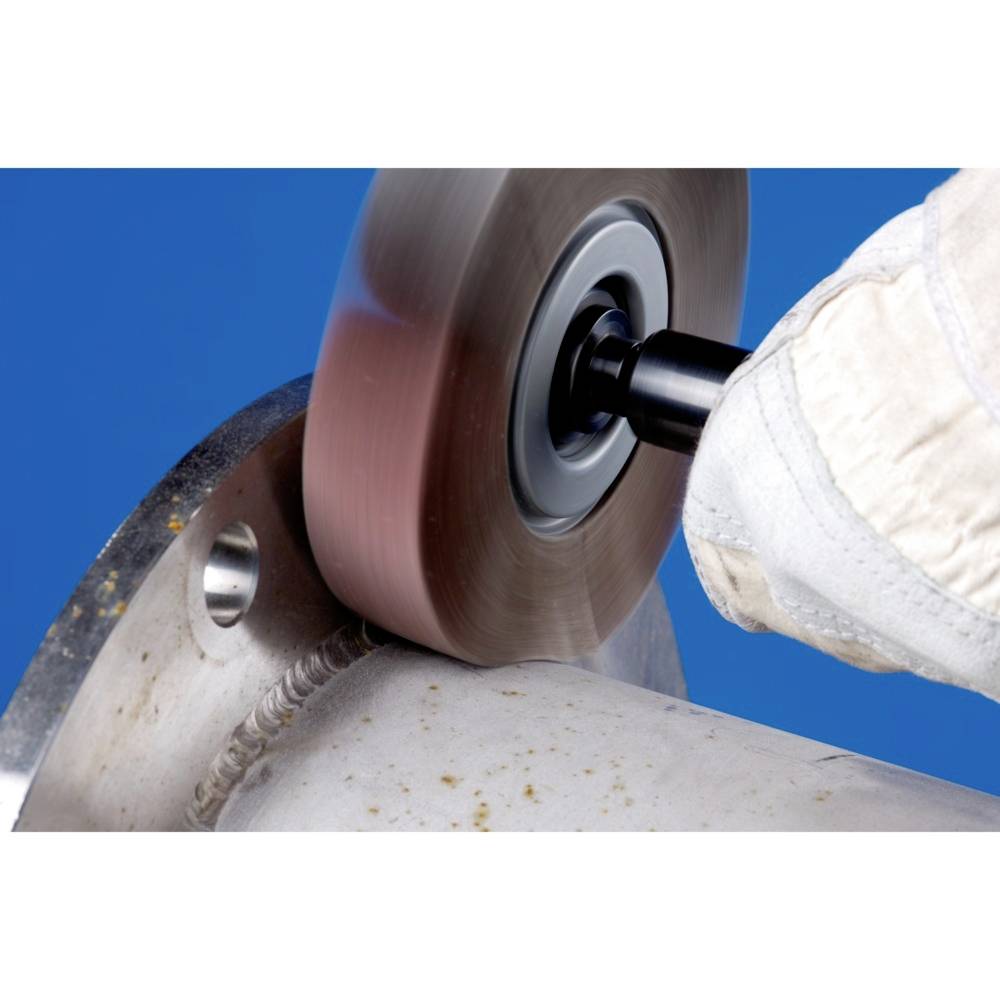 Eine Person verwendet einen Winkelschleifer, um Metall zu polieren. Ein weißer Handschuh schützt die Hand.