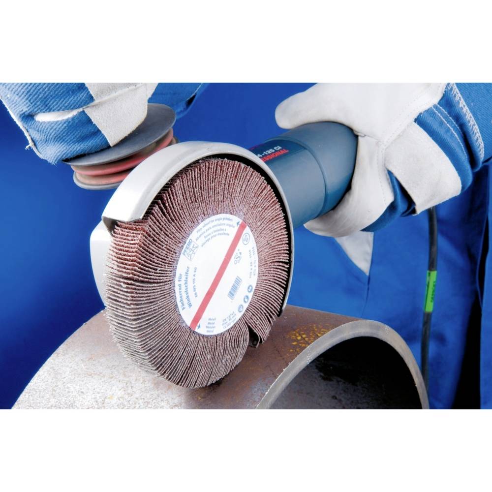 Ein Arbeiter verwendet einen Winkelschleifer mit Lamellenscheibe, um eine Metalloberfläche zu glätten. Arbeiter trägt Handschuhe.