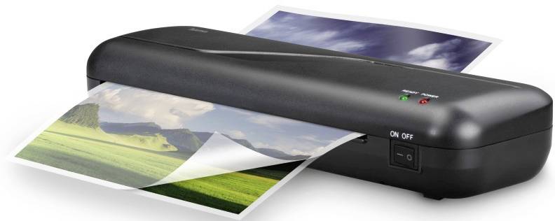 Ein Laminiergerät, das gerade ein Foto laminiert. Das Foto zeigt eine Landschaft mit grünen Wiesen und bewölktem Himmel.