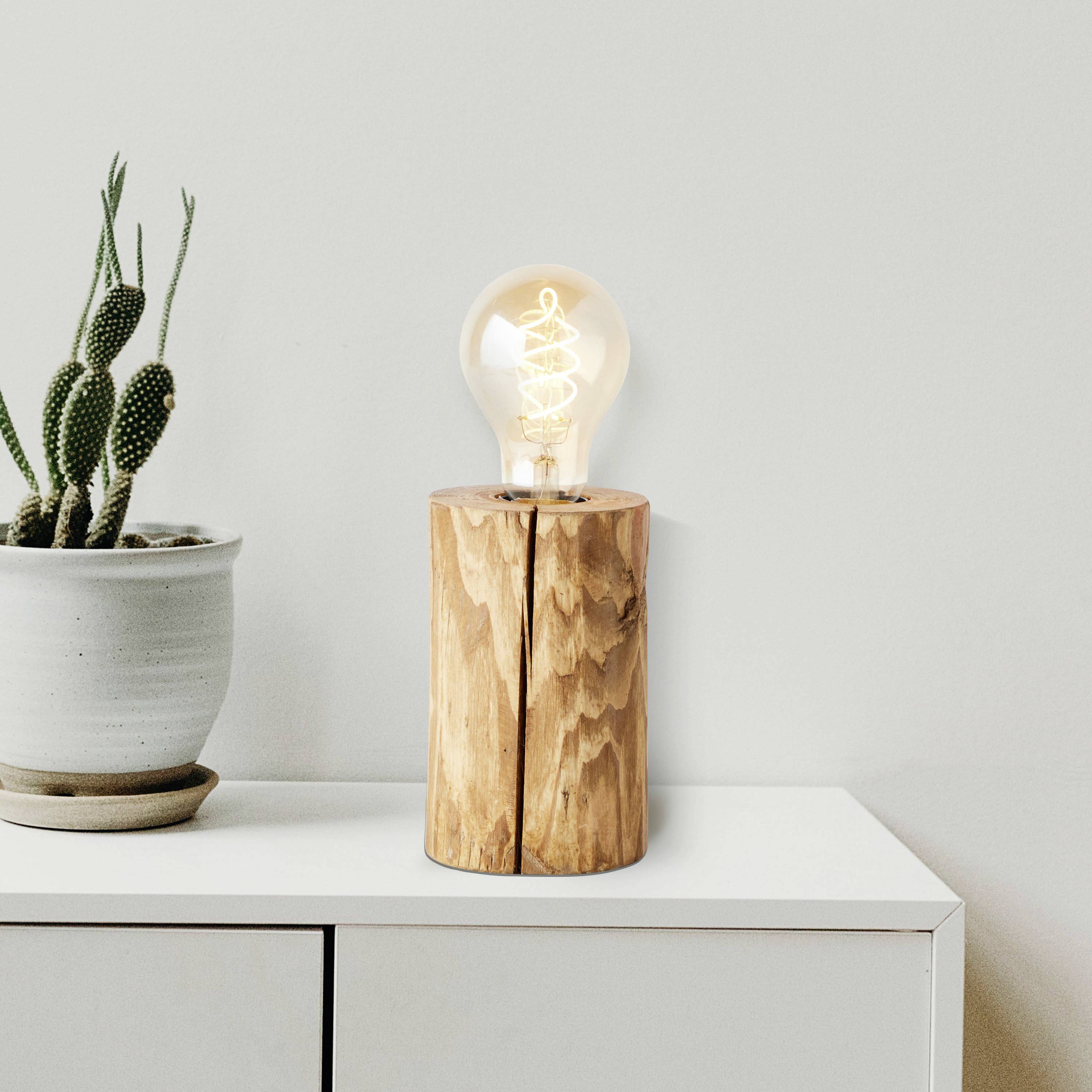 Holztisch mit Kaktuspflanze im Topf und Holzlampe mit Glühbirne. Schlichte, moderne Dekoration in neutralen Farbtönen.