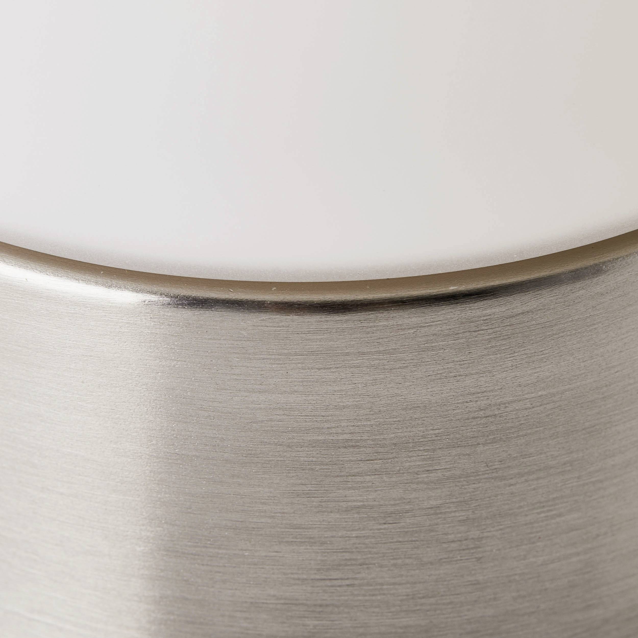 Nahaufnahme einer modernen Lampe mit einer weißen, mattierten Glaskuppel und einem silbernen Metallfuß.