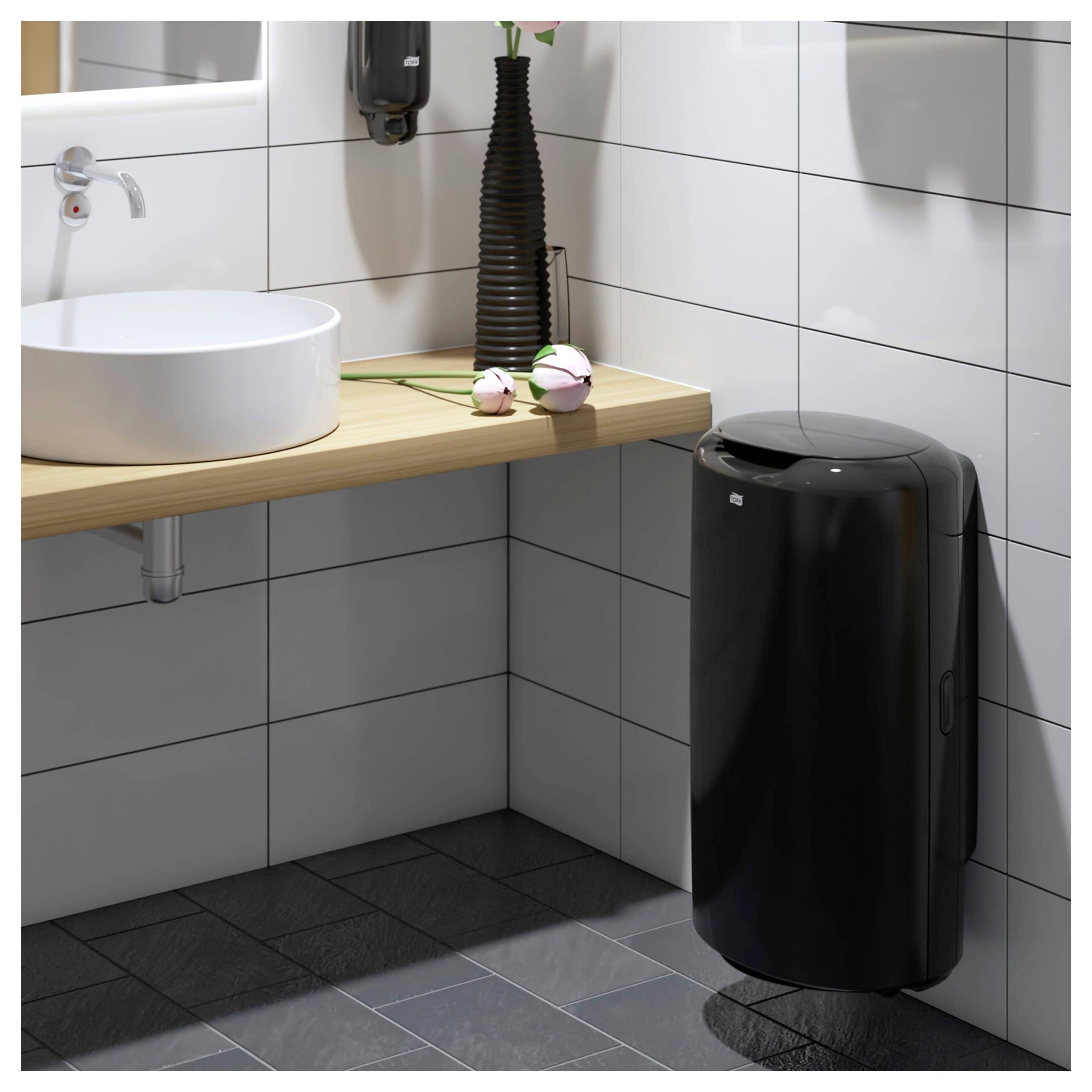 Moderne gekachelte Badezimmerecke mit einem weißen Aufsatzwaschbecken, Holzarbeitsplatte und schwarzem Seifenspender sowie Mülleimer.