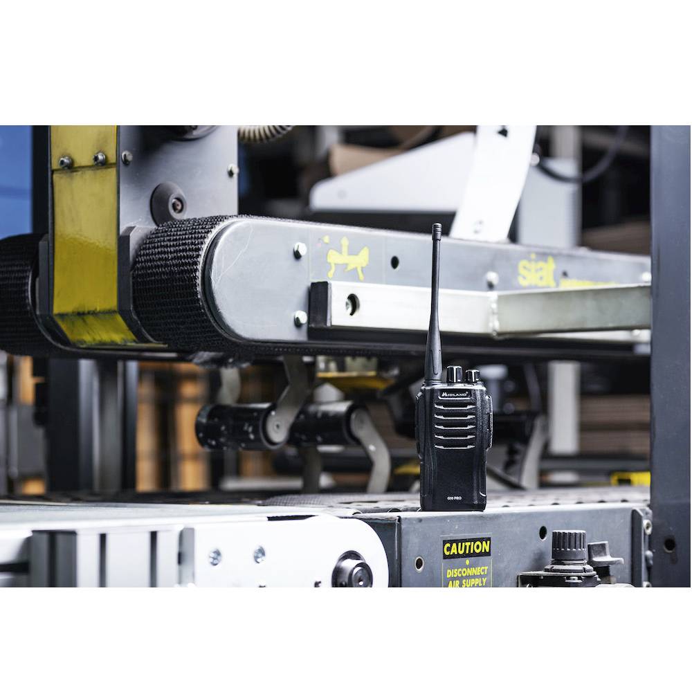 Ein Funkgerät steht auf einem industriellen Förderband in einer Fabrikumgebung, symbolisiert Kommunikation und Kontrolle im Industrieprozess.