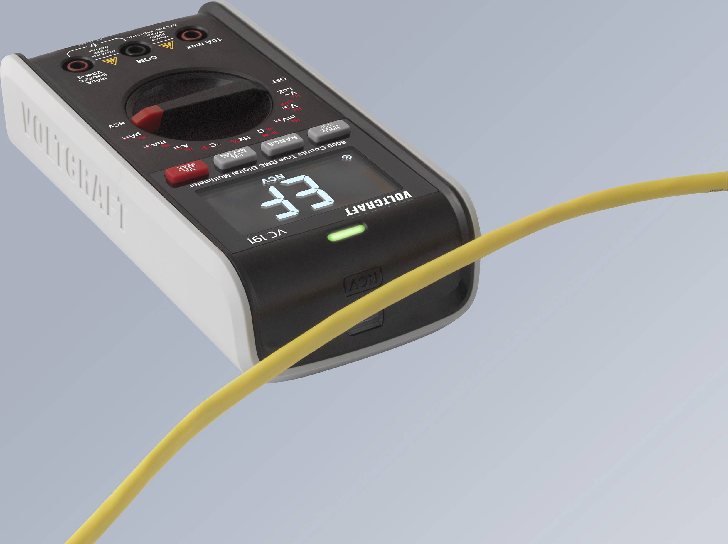 Ein digitales Multimeter zeigt einen Messwert von 33 an. Ein gelbes Kabel verläuft über das Gerät.
