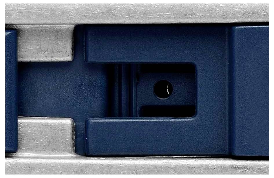 Nahaufnahme einer Metallklammer im Inneren eines Bürohefters, mit einem blauen Gehäuse und silbernen Metallteilen sichtbar.