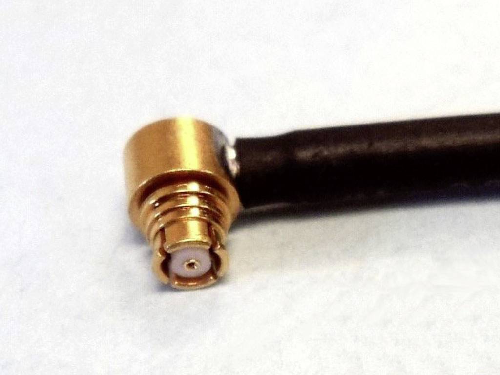 Nahaufnahme eines goldfarbenen Steckers mit schwarzem Kabel. Der Stecker hat einen abgewinkelten Anschluss, wahrscheinlich für HF-Anwendungen.