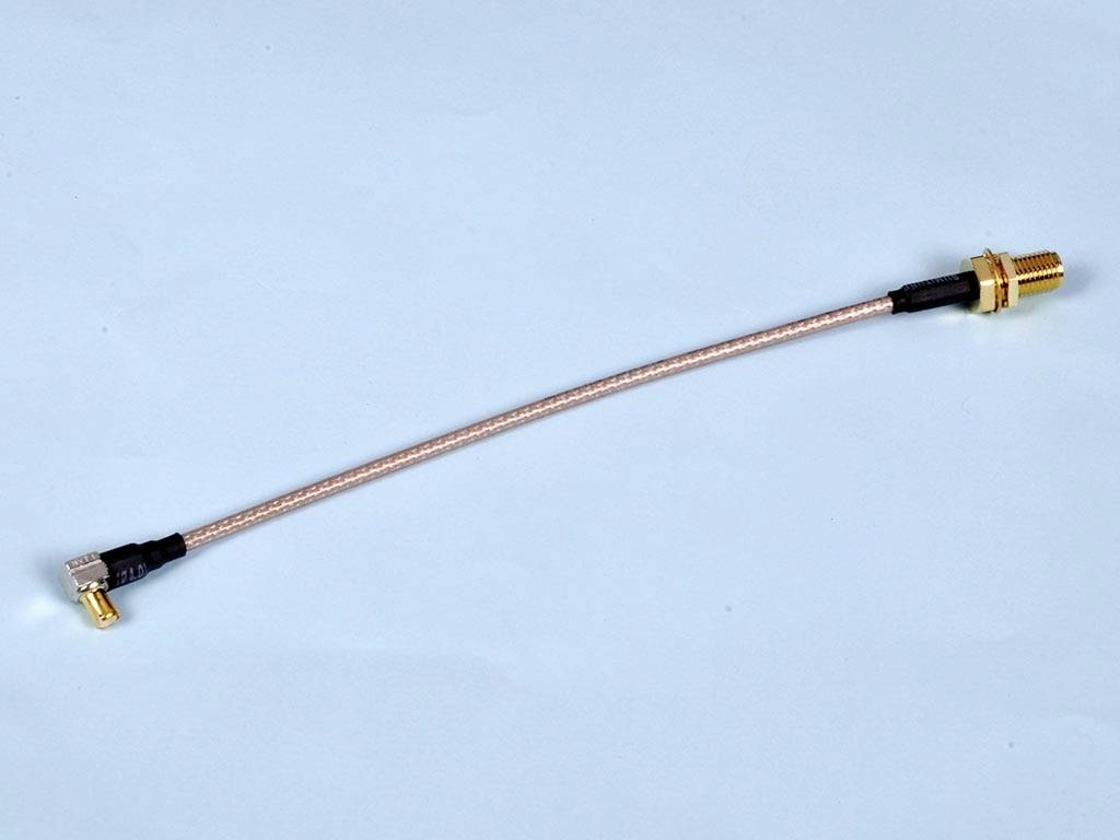 Koaxialkabel mit gewinkeltem Stecker und vergoldetem Anschluss, vor blauem Hintergrund. Geeignet für Hochfrequenzverbindungen.