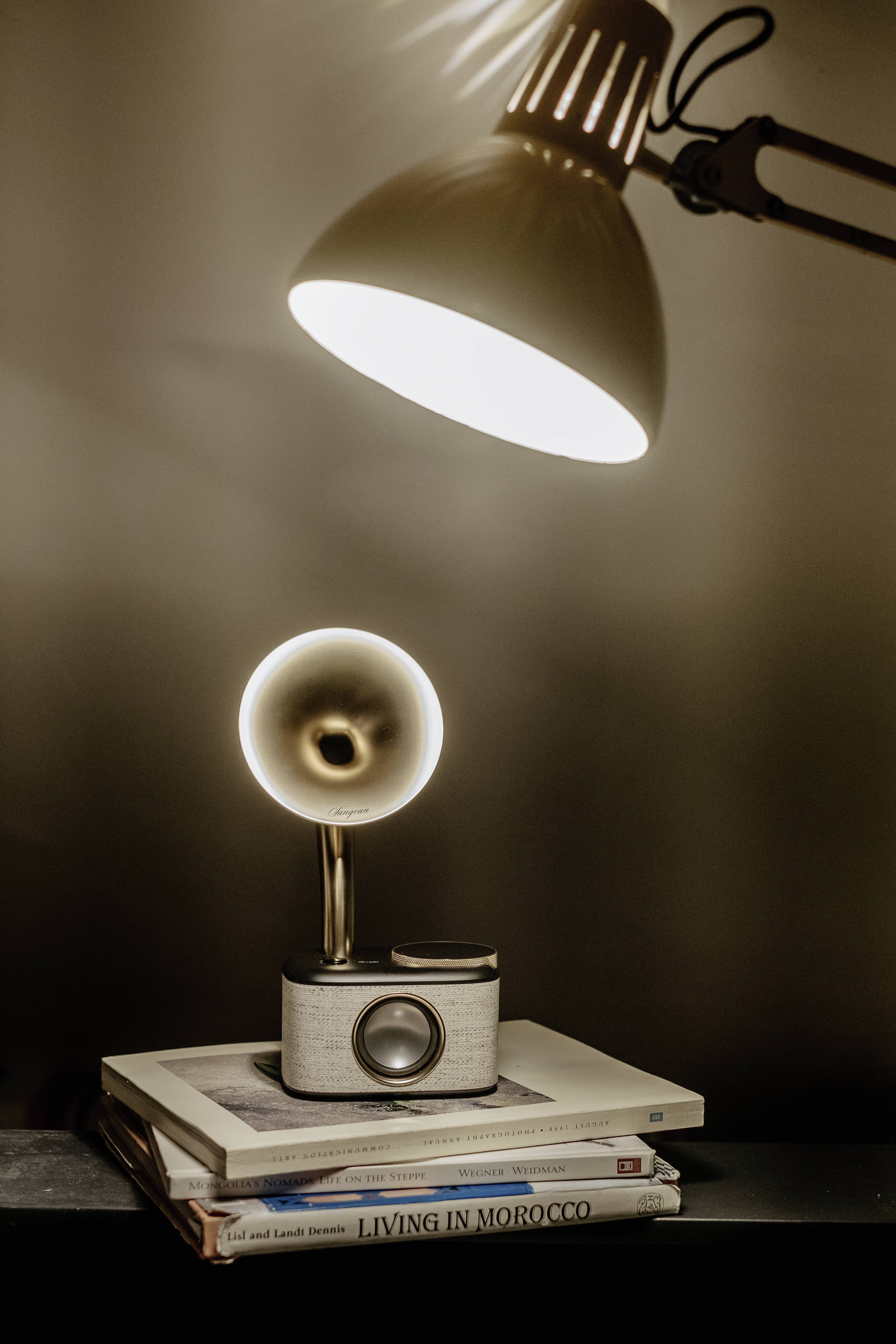 Eine stilvolle, minimalistische Nachttischlampe beleuchtet ein Bücherstapel auf einem Tisch. Die Lampe strahlt warmes, gemütliches Licht aus.