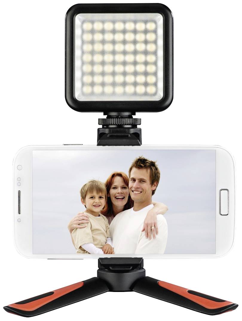 Eine Familie bestehend aus zwei Erwachsenen und einem Kind lächelt in die Kamera, abgebildet auf einem Smartphone mit LED-Licht und Stativ.