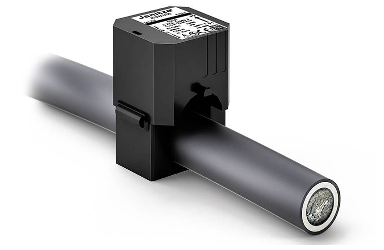 Ein schwarzer Sensor klemmt um ein dickes schwarzes Kabel. Er hat ein Etikett mit technischen Informationen auf der Oberseite.
