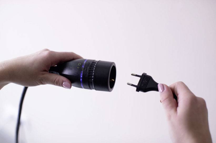 Eine Hand hält eine Steckdose, die andere einen Stecker, bereit zum Einstecken. Beide Hände zeigen aufeinander.