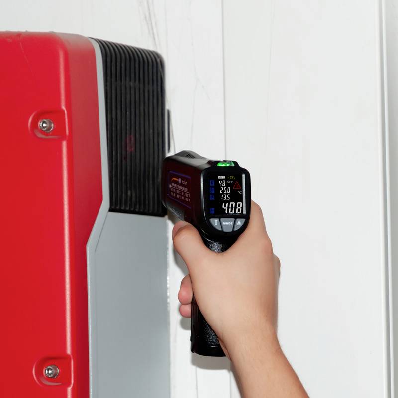 Eine Hand hält ein Infrarot-Thermometer, das auf eine rote Oberfläche gerichtet ist. Das Display zeigt eine Temperatur von 40,8°C an.