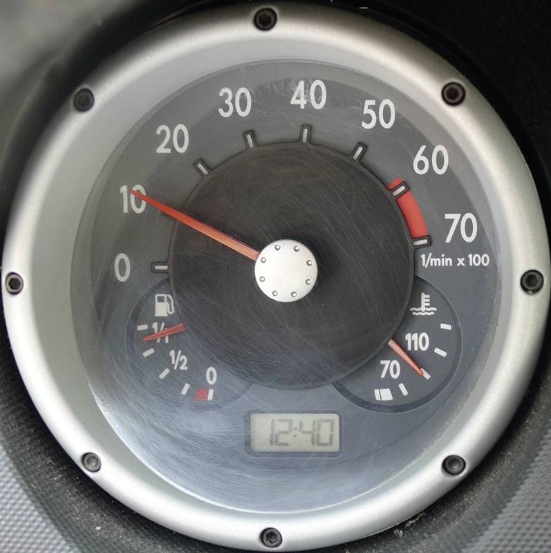 Drehzahlmesser in einem Auto zeigt etwa 1000 U/min. Kleine Anzeigen mit Tankfüllstand bei halb voll und Motortemperatur im Normalbereich. Digitaluhr zeigt 12:40 Uhr.