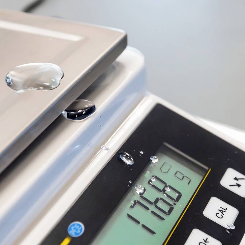 Eine digitale Waage mit einem Wassertropfen auf der Plattform zeigt ein Gewicht von 178,9 g an.