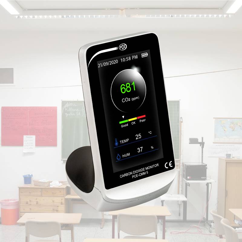 Ein CO2-Monitor auf einem Tisch in einem Klassenzimmer. Der Bildschirm zeigt die CO2-Konzentration in ppm sowie Temperatur und Luftfeuchtigkeit.