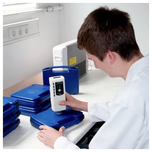Ein Techniker benutzt einen tragbaren medizinischen Scanner, um blaue tragbare Koffer auf einer Laborbench zu testen.