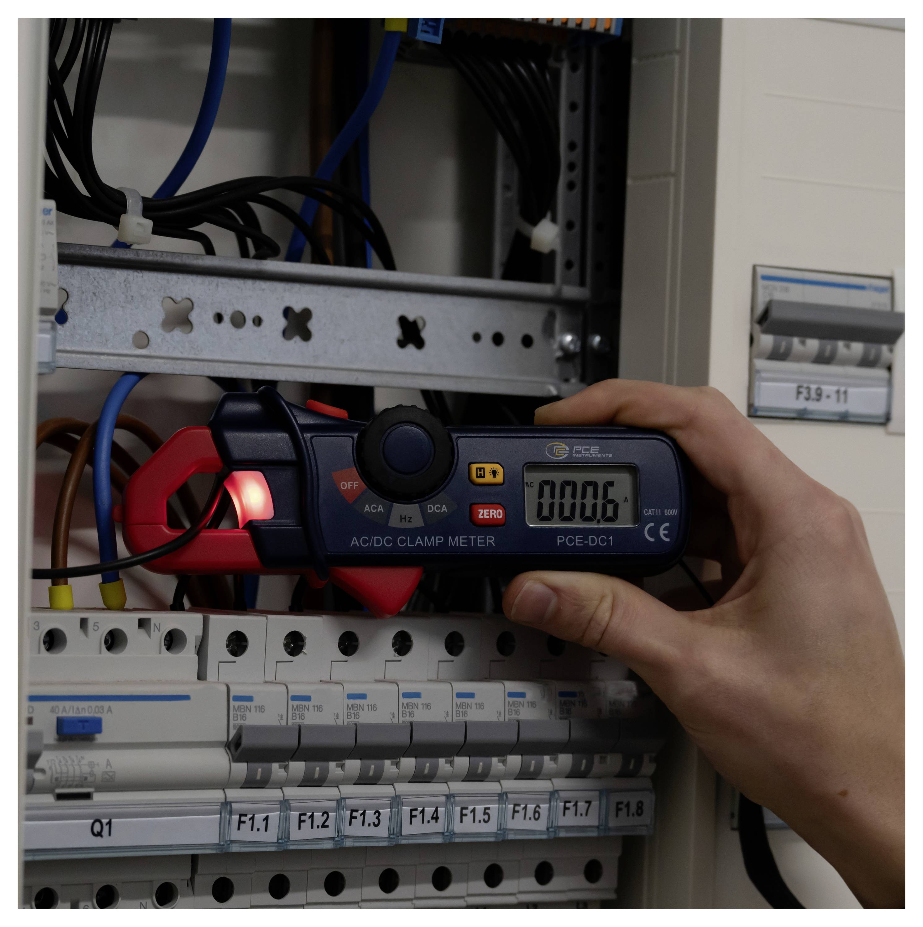 Tragbares AC/DC-Zangenmessgerät zur Messung der Verkabelung innerhalb eines Elektrosteuerschranks in der Nähe von gekennzeichneten Schutzschaltern.
