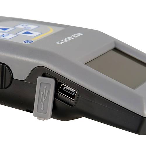 Nahaufnahme eines elektronischen Geräts mit USB-Anschluss auf der Seite. Das Gerät hat Tasten und ein Display auf der Oberseite.