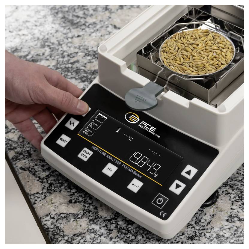 Hand bedient einen Getreidefeuchtemesser mit einer Probenschale voll Weizen oben drauf, wobei auf dem Display eine digitale Prozentanzeige zu sehen ist.