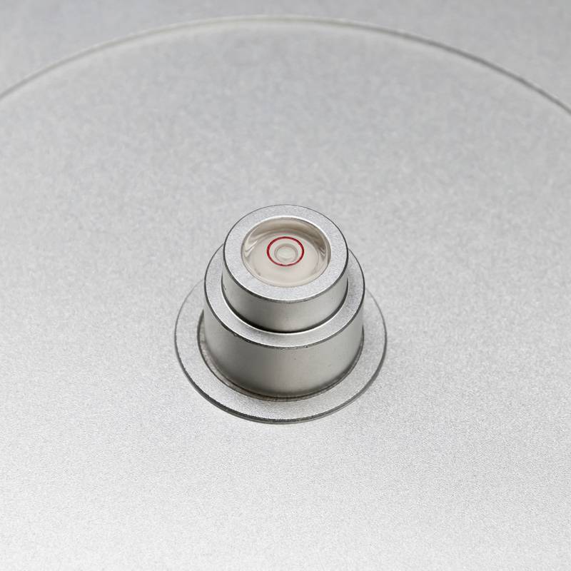 Nahaufnahme eines silbernen Zylinderobjekts mit einem kleinen, kreisförmigen roten Detail in der Mitte. Glatte, metallische Oberfläche.