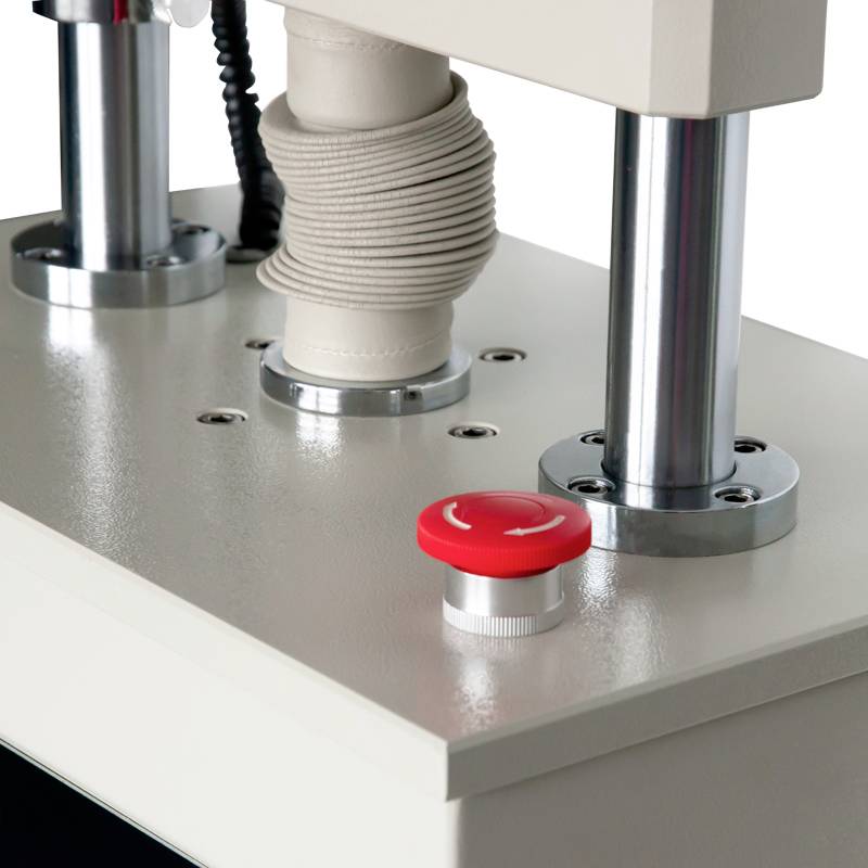 Blick auf eine industrielle Maschine mit silbernen Metallteilen und einem roten Knopf. Diese Elemente sind Teil eines größeren Geräts.