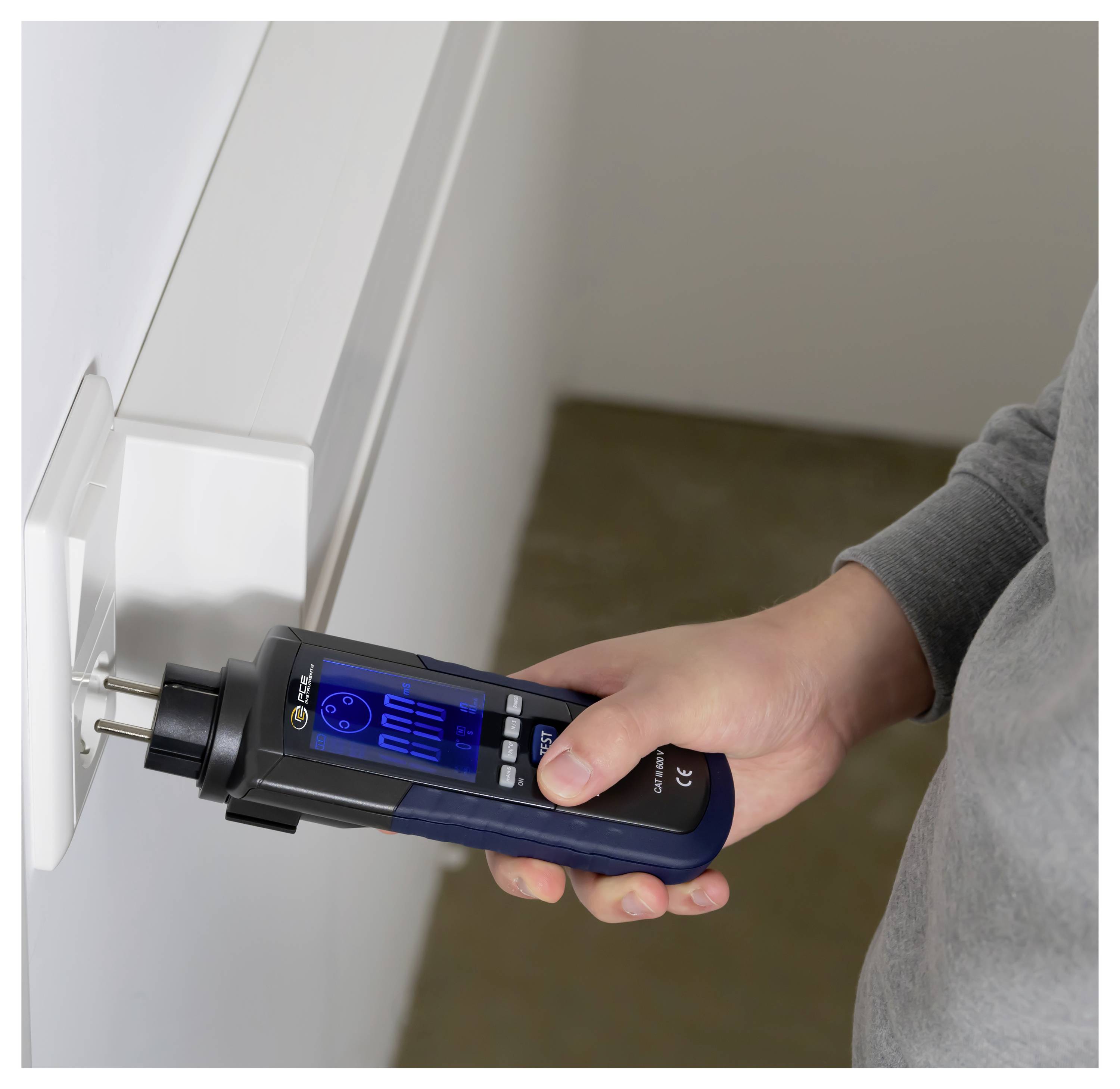 Person, die ein Stecker-Strommessgerät verwendet, um den Stromverbrauch von einer Wandsteckdose zu messen.