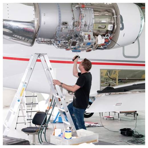 Techniker auf einer Leiter, der Verdrahtung an einem Flugzeugtriebwerk in einer Wartungshalle inspiziert und repariert.