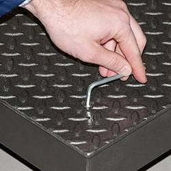 Eine Hand hält einen kleinen Haken auf einer rutschfesten Metalloberfläche.