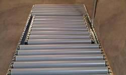 Förderband mit Metallrollen in einem Lager. Es scheint ungenutzt und bereit für Waren- oder Materialtransport zu sein.