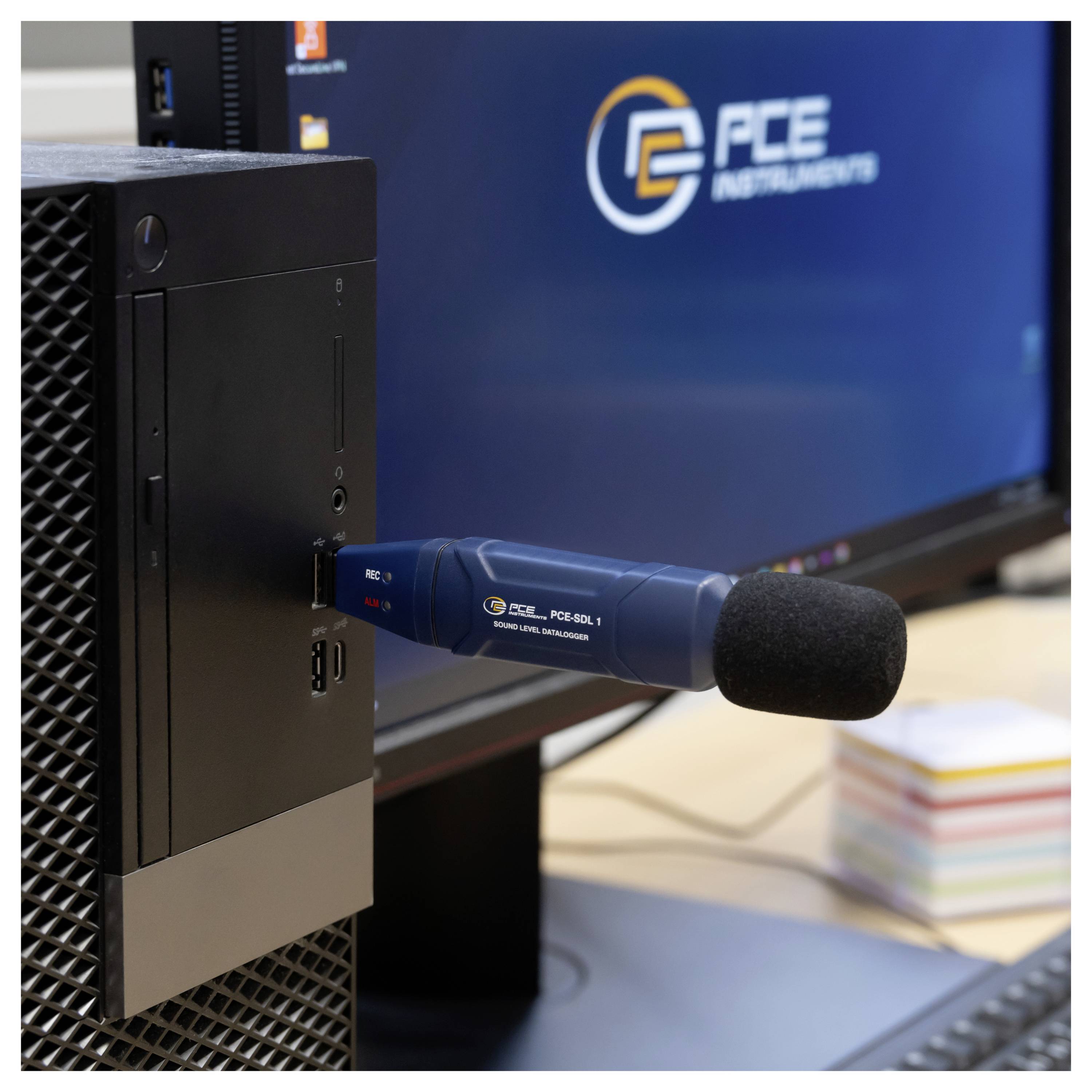 Ein Desktop-Mikrofon ist neben einem Monitor, der das GFE Instruments-Logo anzeigt, in einen Computer eingesteckt.