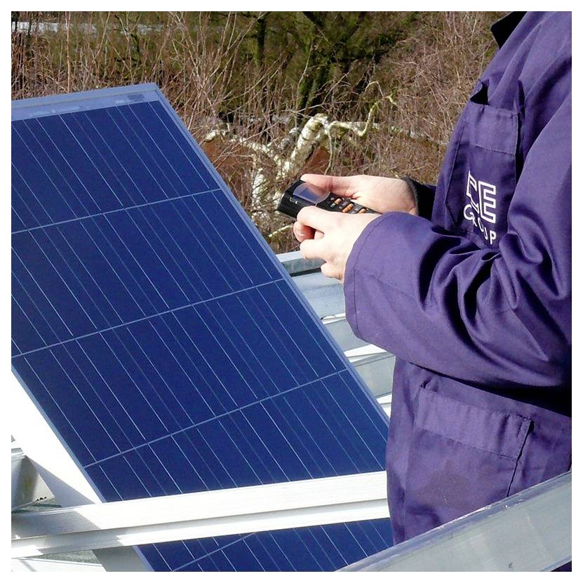 Person in einer Jacke, die ein tragbares Gerät verwendet, um ein Solarpanel im Freien zu inspizieren.