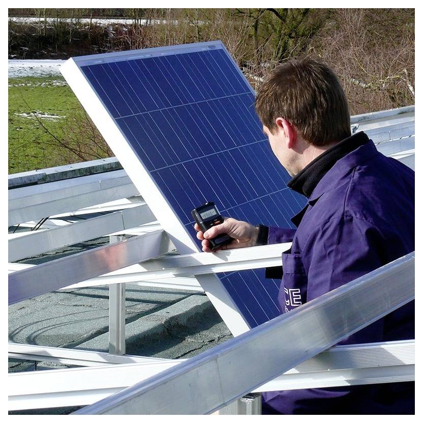 Ein Mann inspiziert ein Dachsolar-Panelgestell mit einem tragbaren Messgerät und überprüft die Installation.