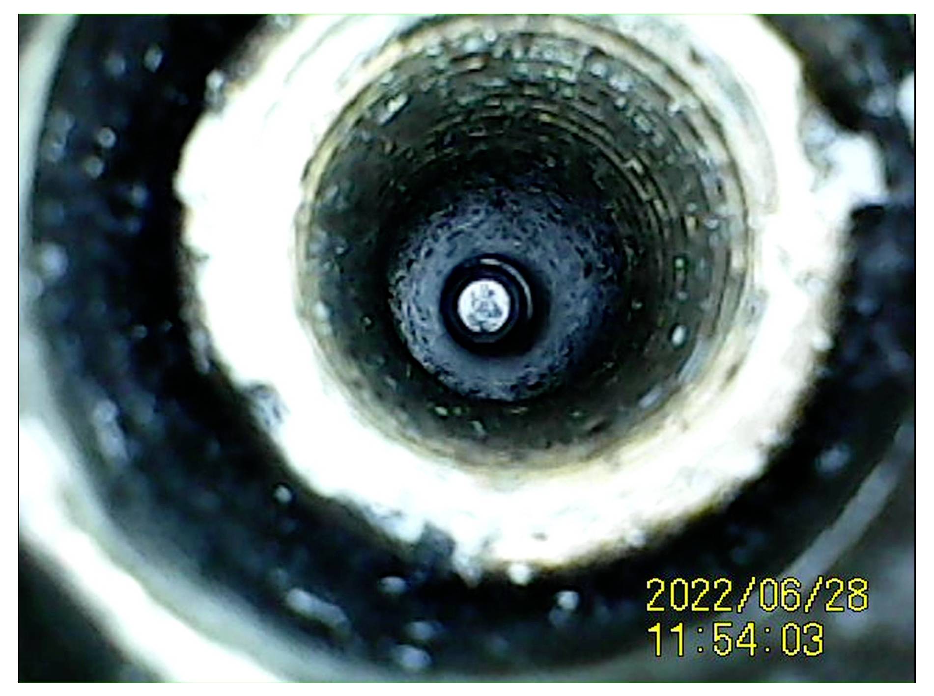 Nahaufnahme im Inneren eines kreisförmigen Rohrs oder einer Röhre, die einen dunklen tunnelartigen Innenraum mit einem kleinen hellen Zentrum und einem Datums-Zeit-Stempel „2022/06/28 11:54:03