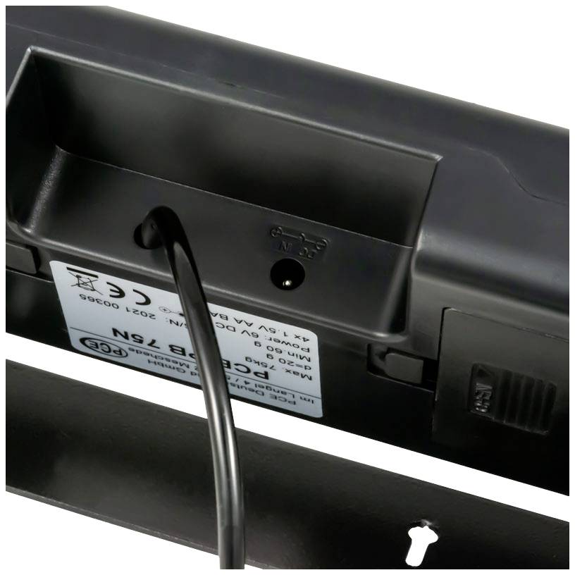 Ein Kabelanschluss an einem elektronischen Gerät, sichtbar mit einem Etikett mit technischen Spezifikationen und Symbolen.