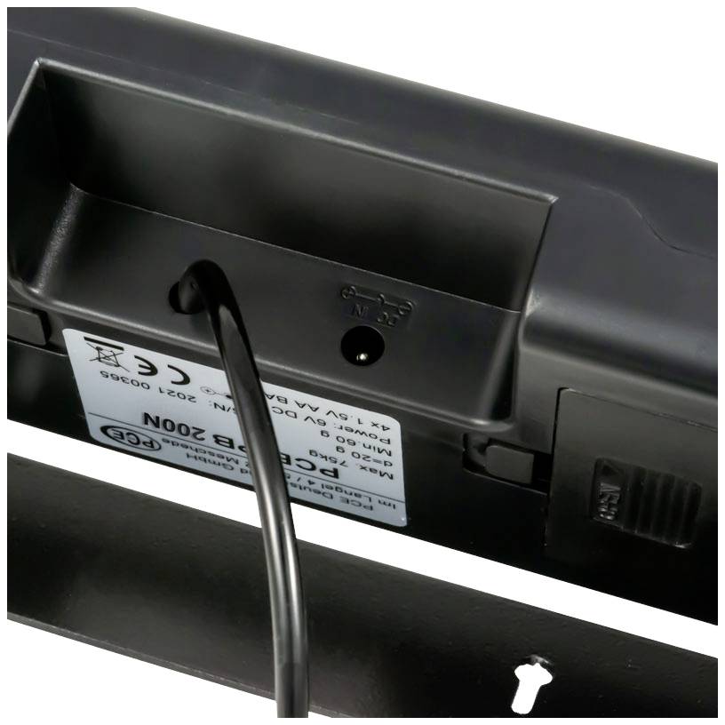 Ein schwarzer Kabelstecker wird in die Rückseite eines elektronischen Geräts eingesteckt, das an der Wand montiert werden kann.