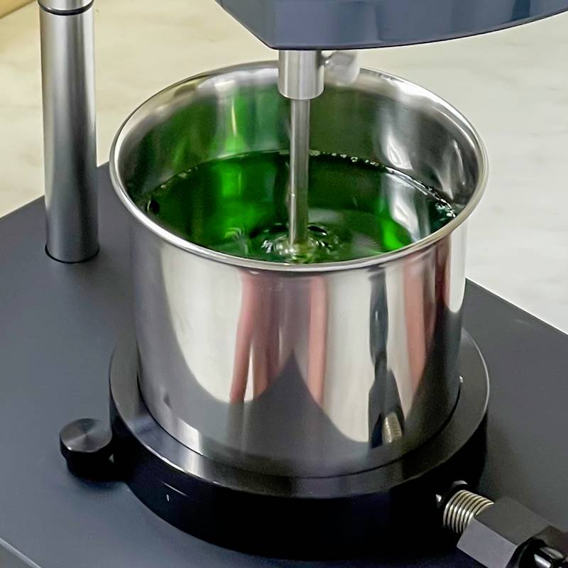 Ein Metalltopf mit grüner Flüssigkeit wird von einem Rührgerät gemischt.