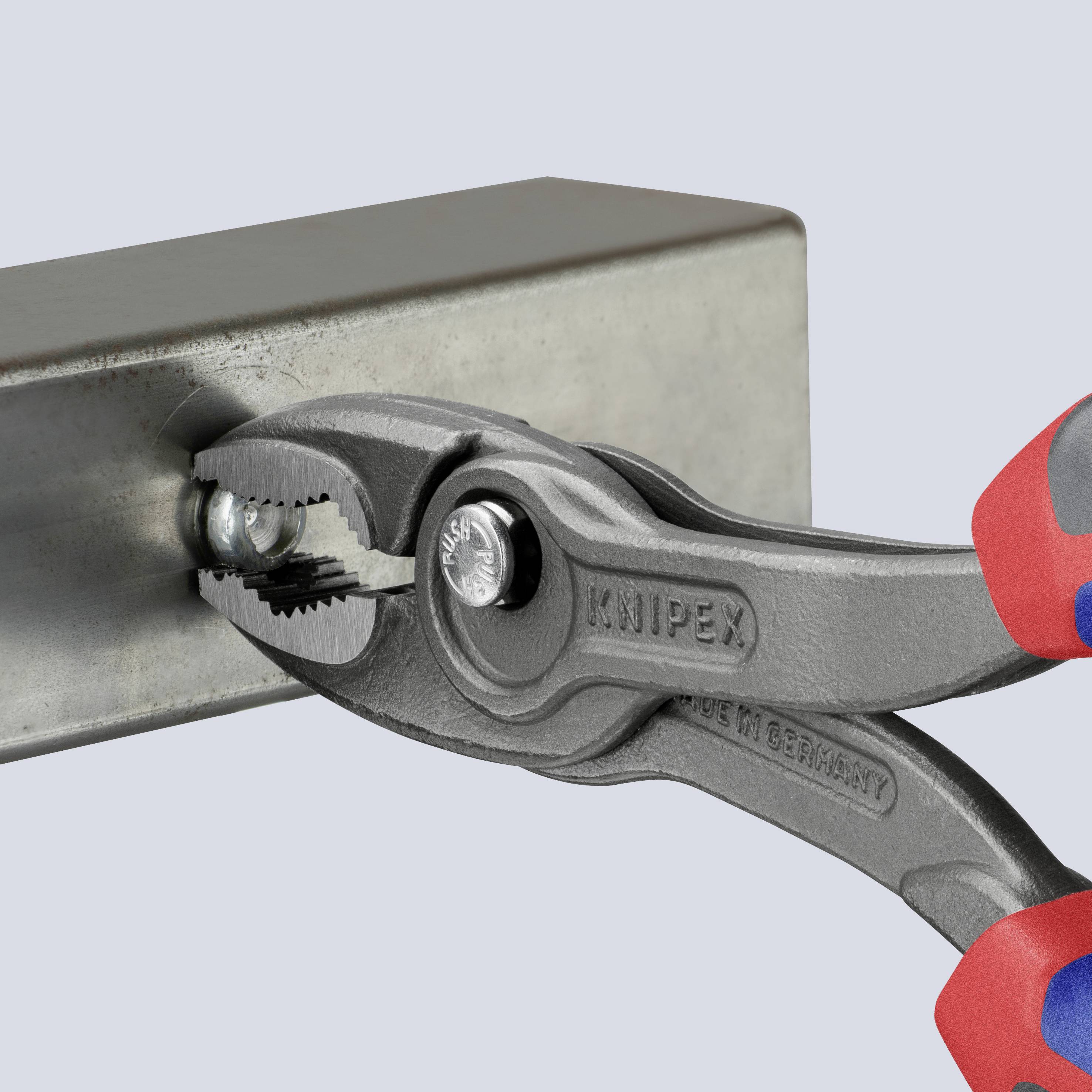 Zange hält eine Metallschiene fest. Die Zangenmarke 'Knipex' ist sichtbar. Ein Teil einer Hand in einem roten Handschuh hält die Zange.