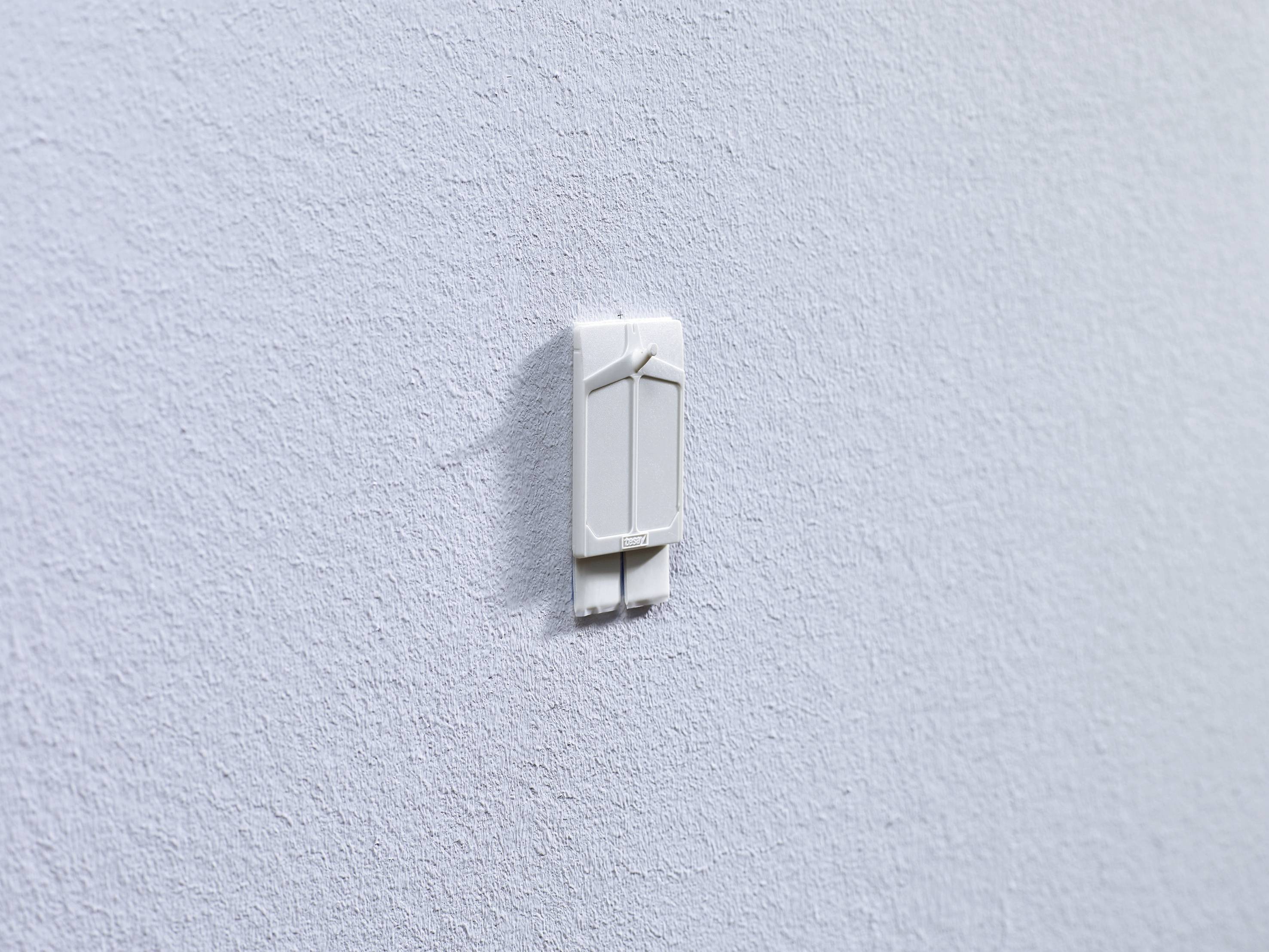 Ein weißer Lichtschalter an einer grauen Wand.