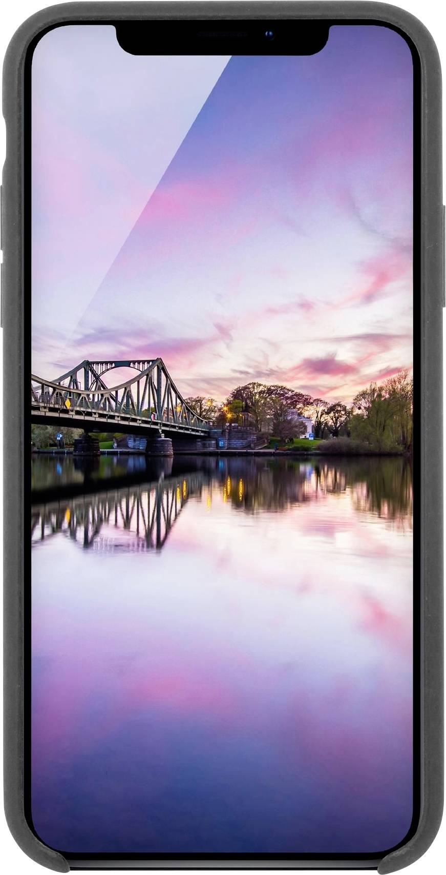 Ein Smartphone zeigt eine wunderschöne Flusslandschaft bei Sonnenuntergang mit einer Brücke und Bäumen, die sich im Wasser spiegeln.