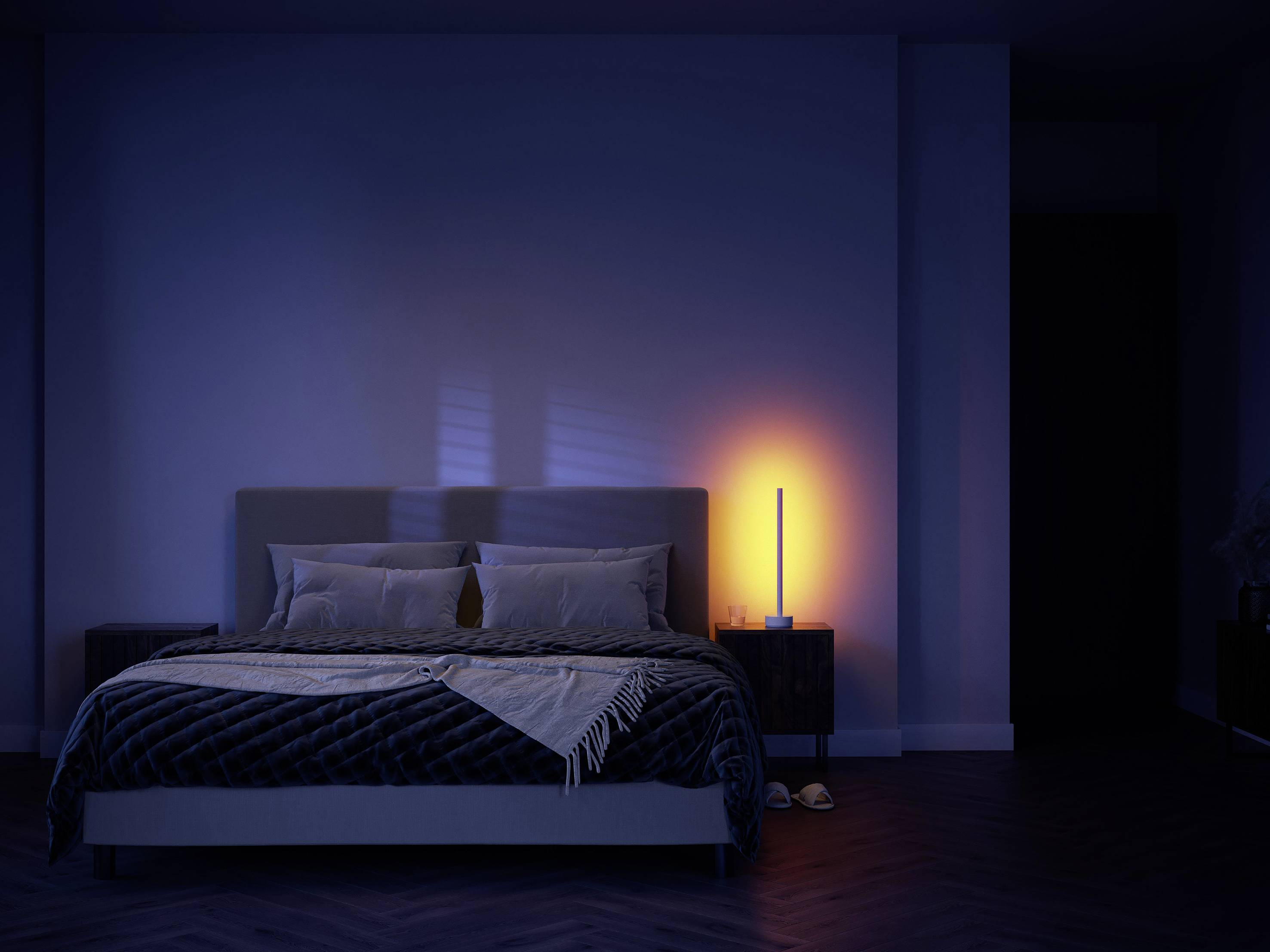 Dunkles Schlafzimmer mit beleuchtetem Nachttischlampe rechts neben dem Bett, wirft warmes Licht auf eine moderne, minimalistische Einrichtung.