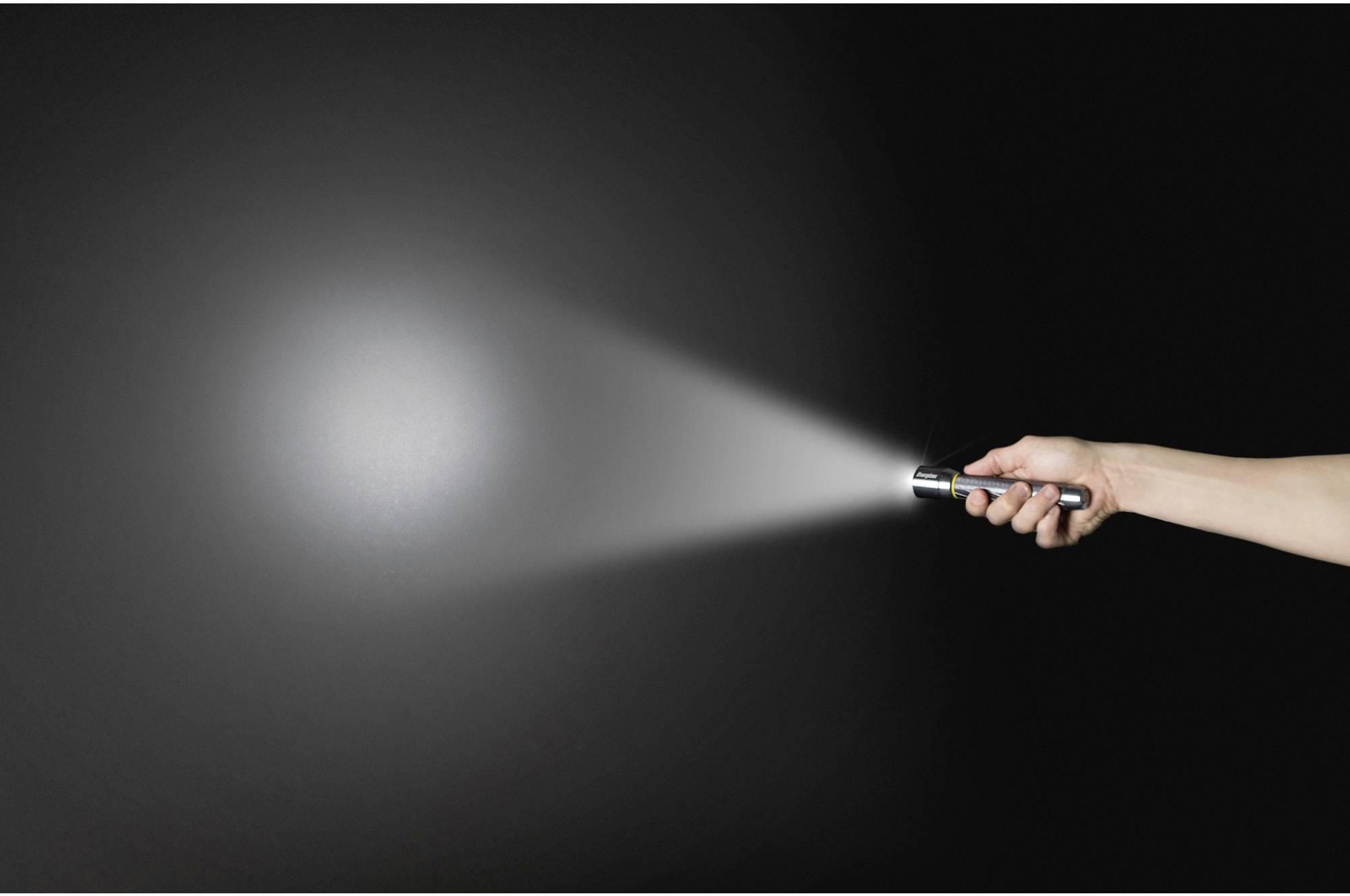 Eine Hand hält eine Taschenlampe in einem dunklen Raum. Der Lichtstrahl leuchtet nach rechts und hebt einen Abschnitt der Wand hervor.