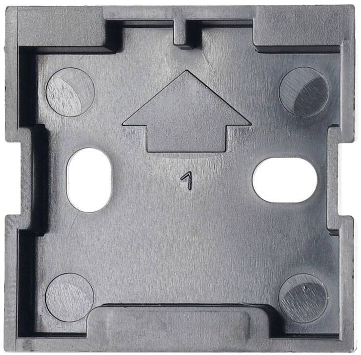 Ein schwarzes Kunststoffteil mit einer Pfeilspitze in der Mitte, gekennzeichnet mit der Zahl 1. Zwei ovale Aussparungen befinden sich darunter.