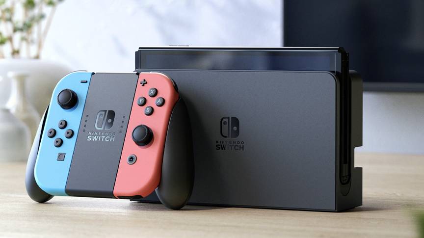 Eine Nintendo Switch-Konsole auf einem Tisch, mit einem blauen und einem roten Joy-Con-Controller angebracht. Im Hintergrund unscharfe Einrichtung.