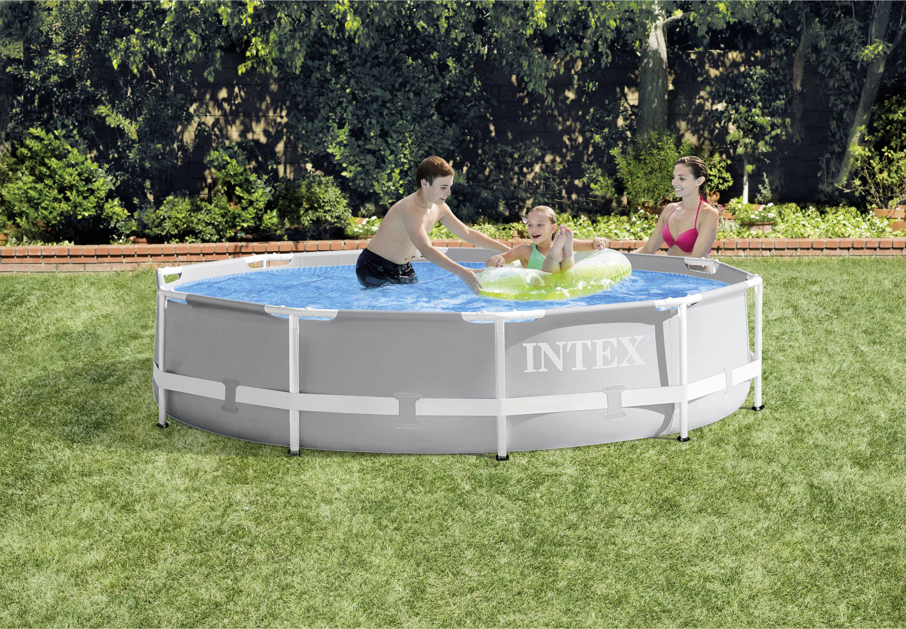 Drei Menschen spielen in einem runden Aufstellpool im Garten. Eine Person taucht, während die anderen am Beckenrand sitzen und zusehen.