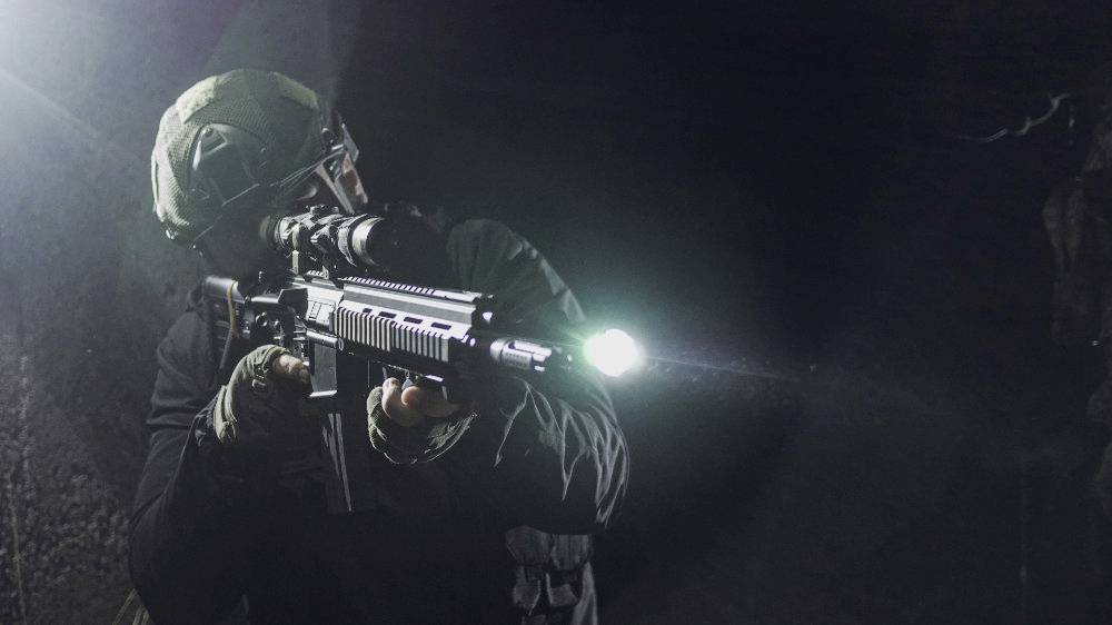 Soldat in Tarnkleidung zielt mit einem Gewehr in einem dunklen Raum, Taschenlampe befestigt. Konzentrierter Gesichtsausdruck, dramatische Beleuchtung.